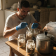 Man inoculating mushroom jars in kitchen workspace
