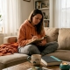 Woman journaling on sofa in bright living room